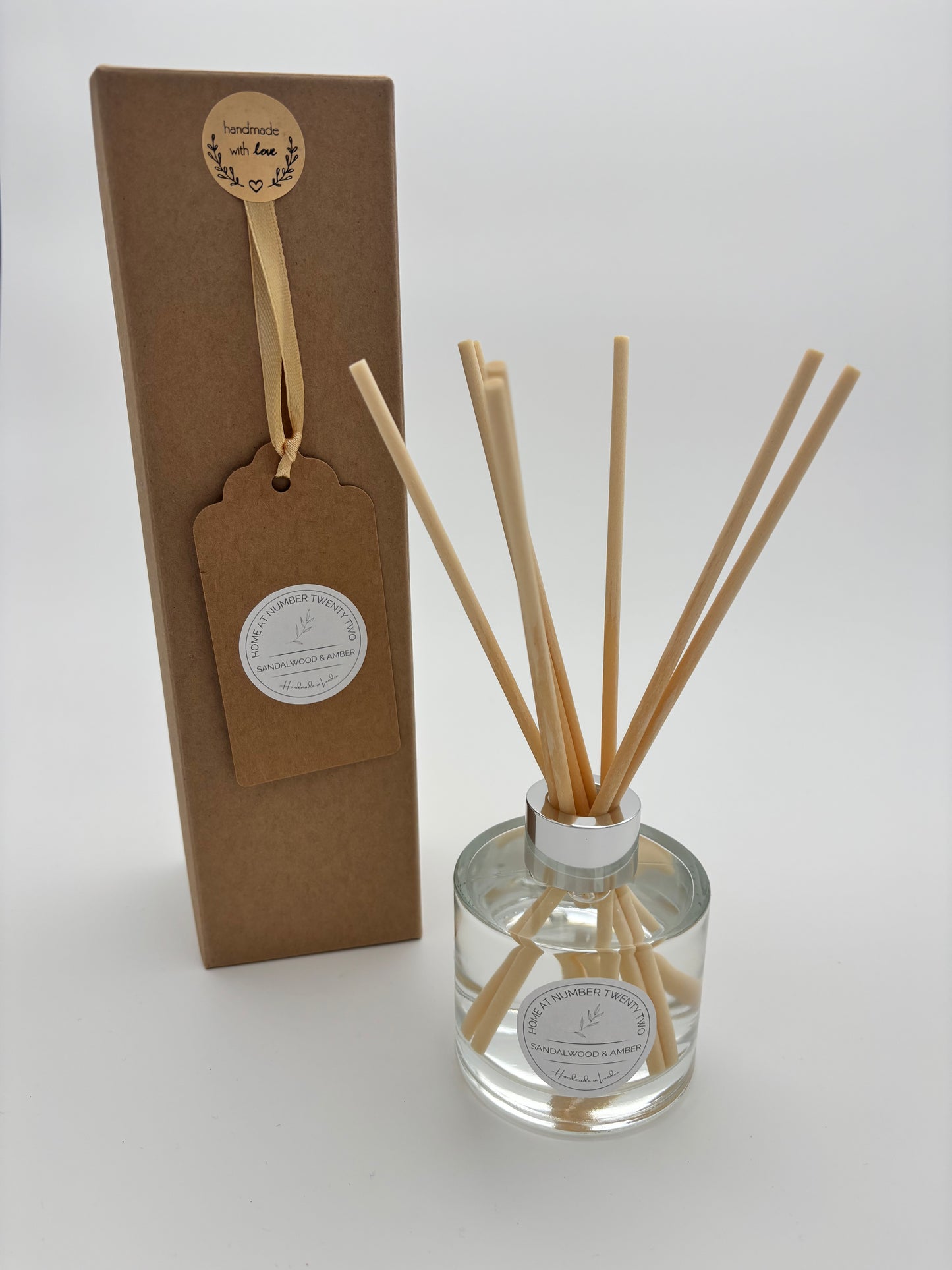 Sandalwood and Amber Reed Diffuser in clear glass bottle, with silver cap, natural coloured reeds and branded Home at Number Twenty Two kraft gift box