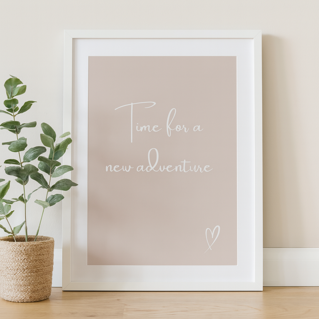 Framed print with 'Time for a new adventure' text on a taupe background, placed indoors.