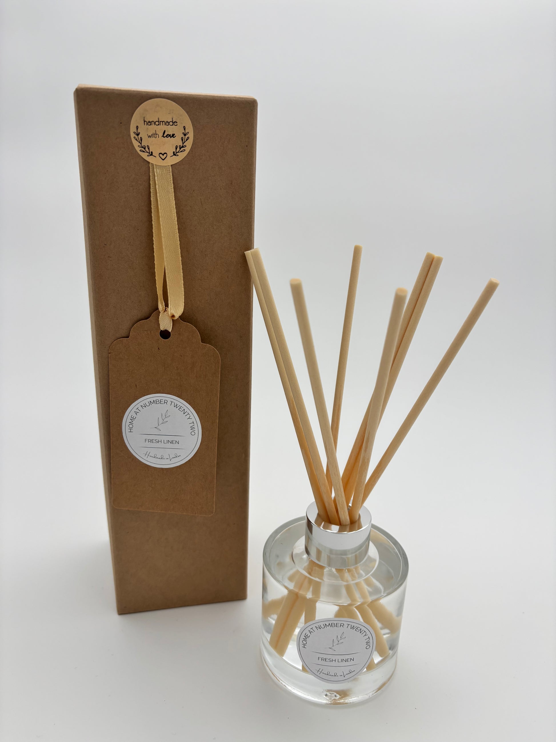 Fresh Linen Reed Diffuser in clear glass bottle, with silver cap and natural coloured reeds, alongside Home at Number Twenty Two kraft gift box