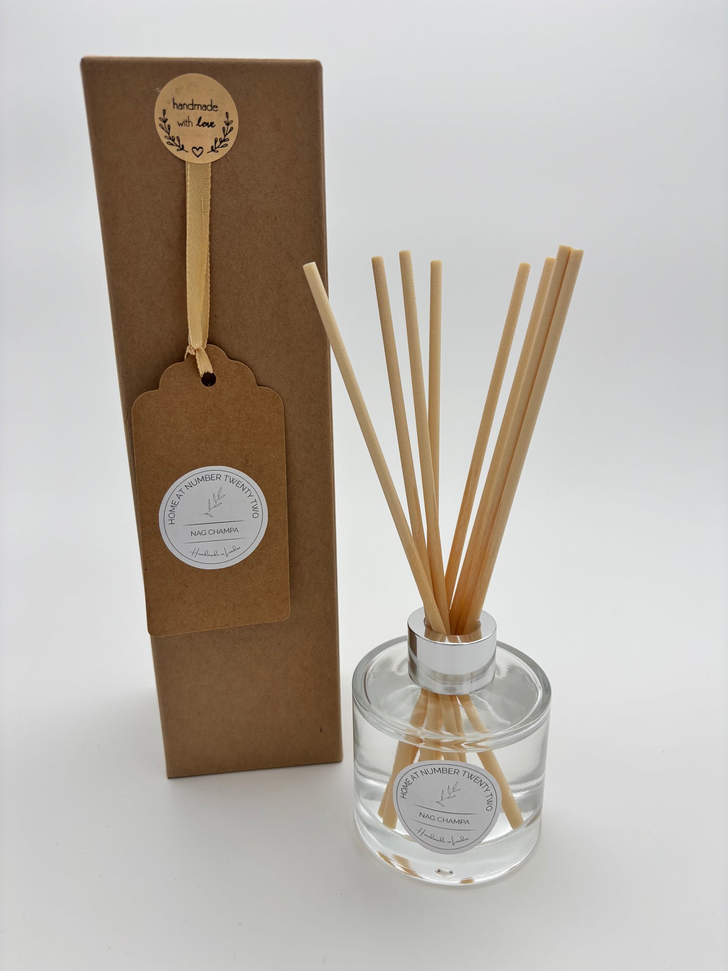 Nag Champa Reed Diffuser in glass circular bottle, with silver cap and natural coloured reeds, alongside kraft Home at Number Twenty Two gift box