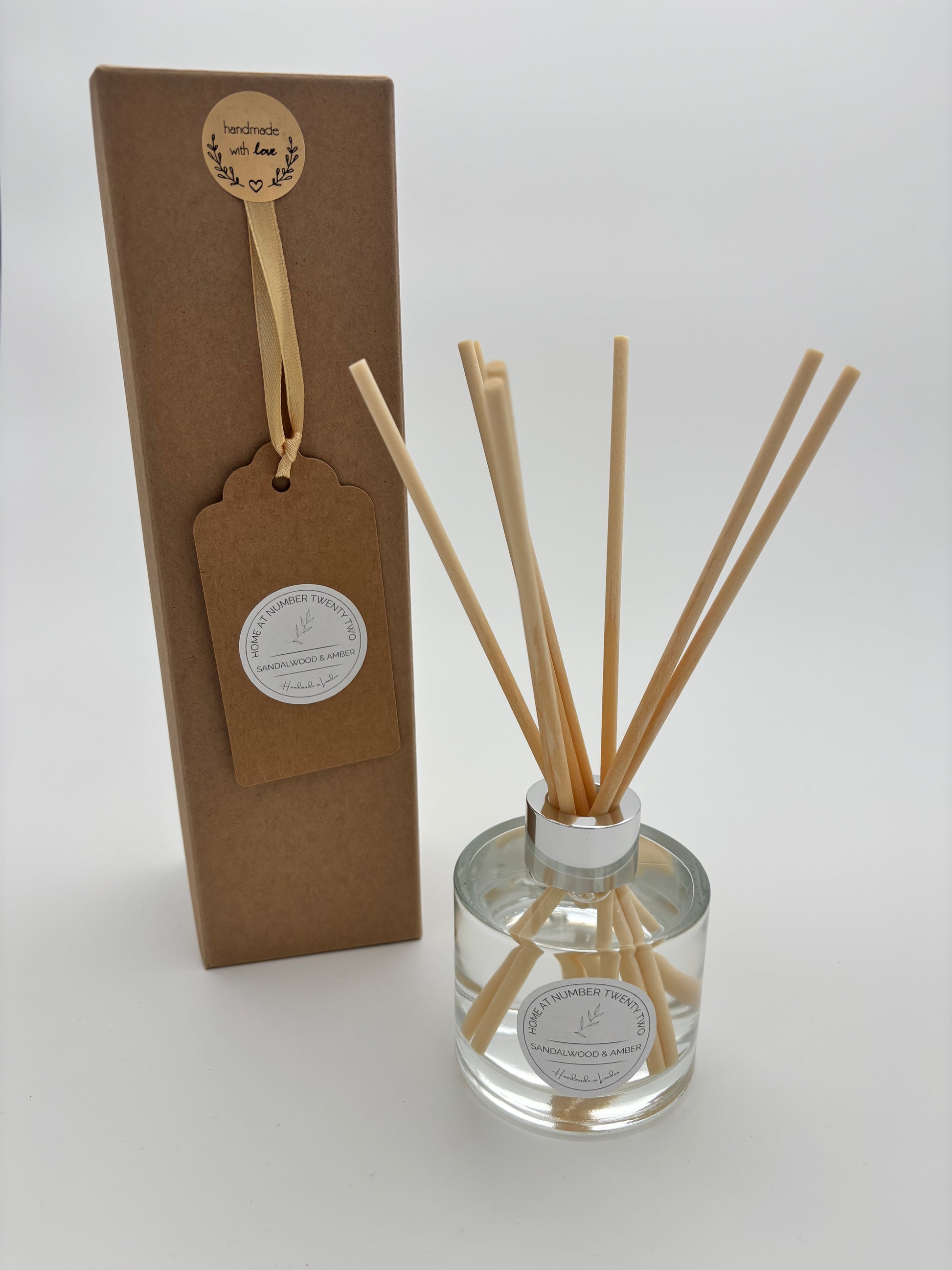 Sandalwood and Amber Reed Diffuser in clear glass bottle, with silver cap, natural coloured reeds and branded Home at Number Twenty Two kraft gift box