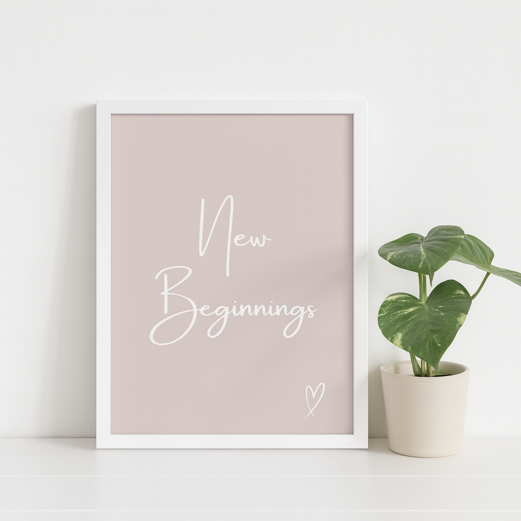 Framed print with 'New Beginnings' text on a light pink background, next to a potted plant.