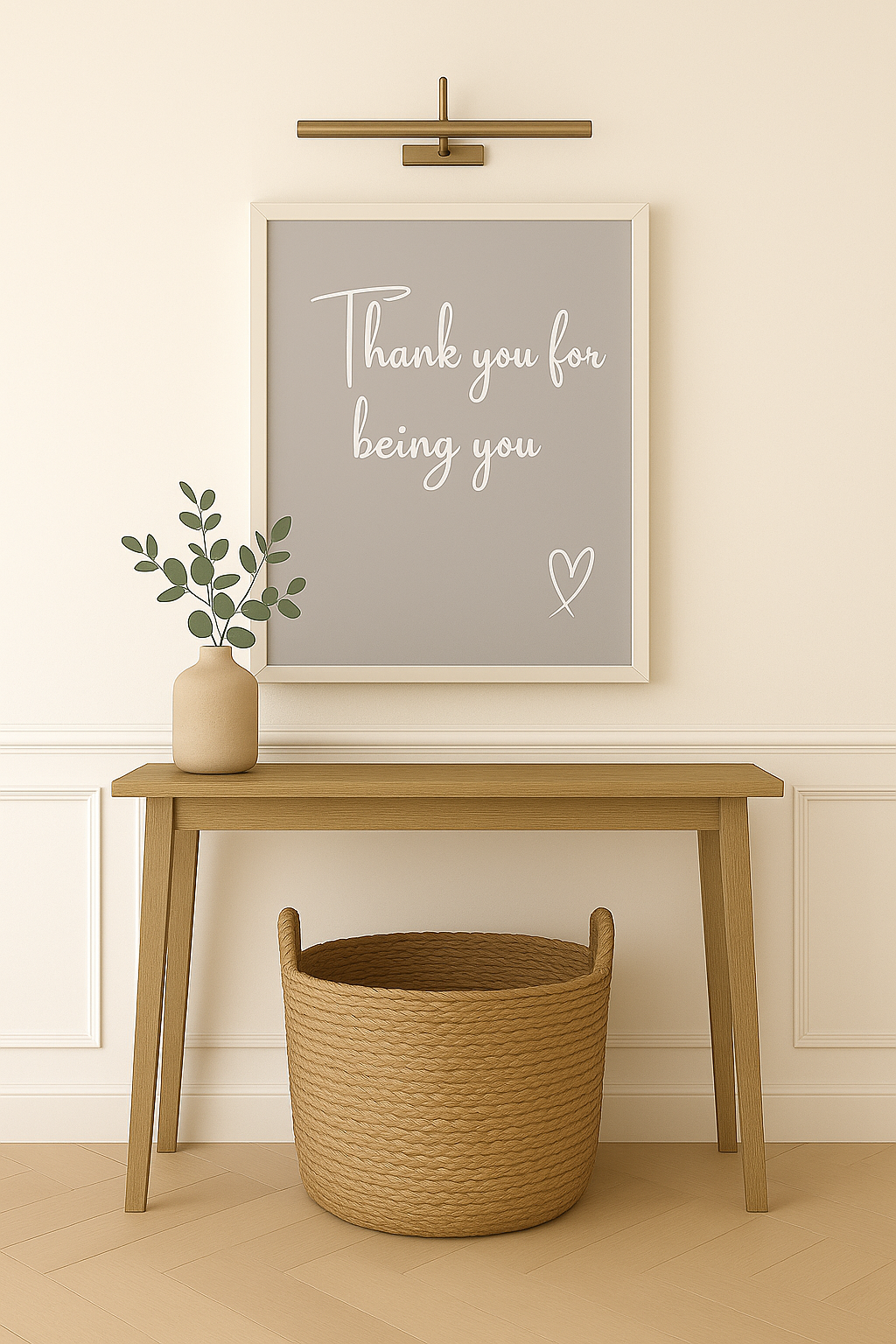 Wooden table with a woven basket and a vase with greenery, framed artwork on the wall ''Thank you for being you'' in white calligraphy font with white hand-drawn heart on a grey background