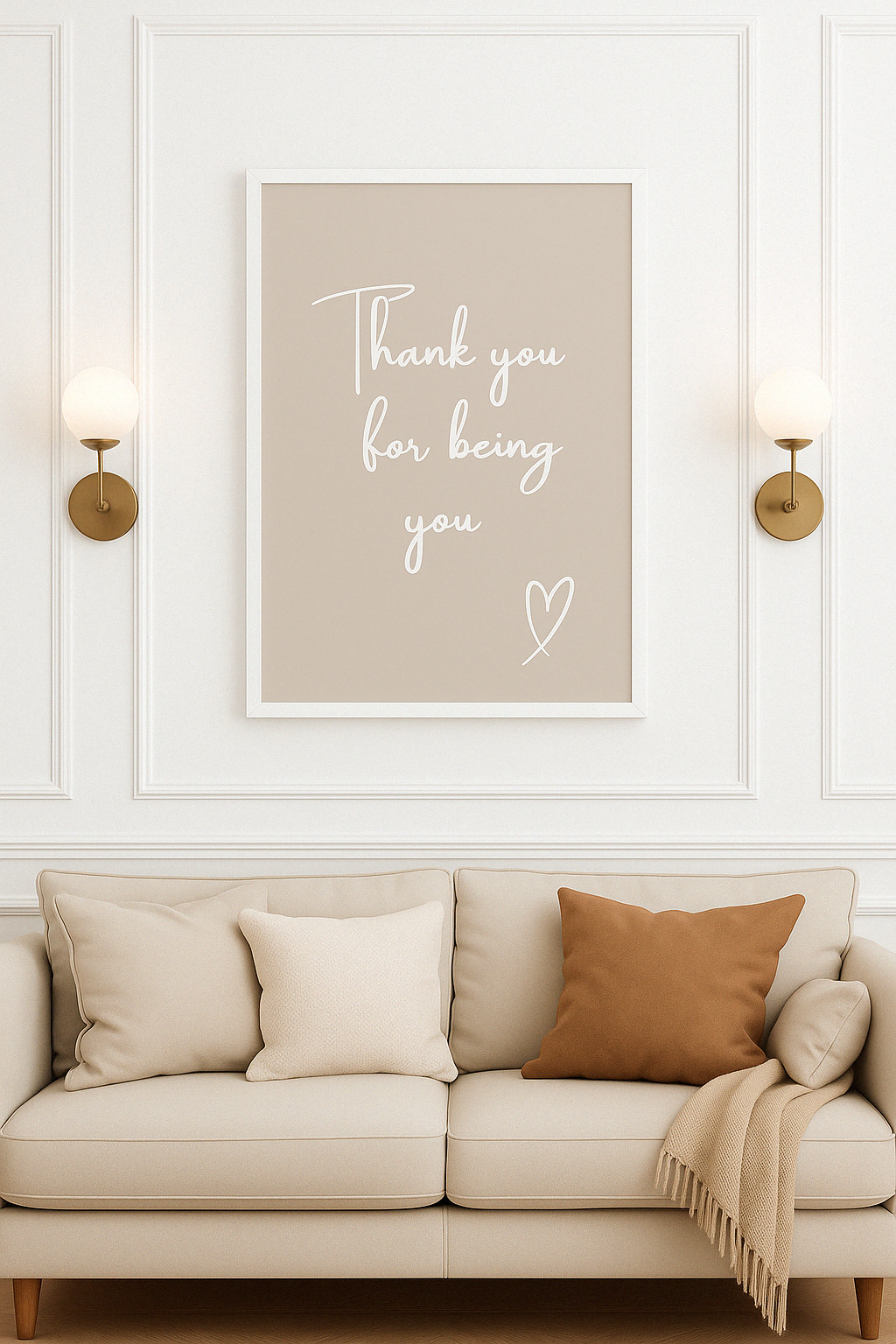 Beige sofa with decorative pillows and a framed quote ''Thank you for being you'', on a white wall.