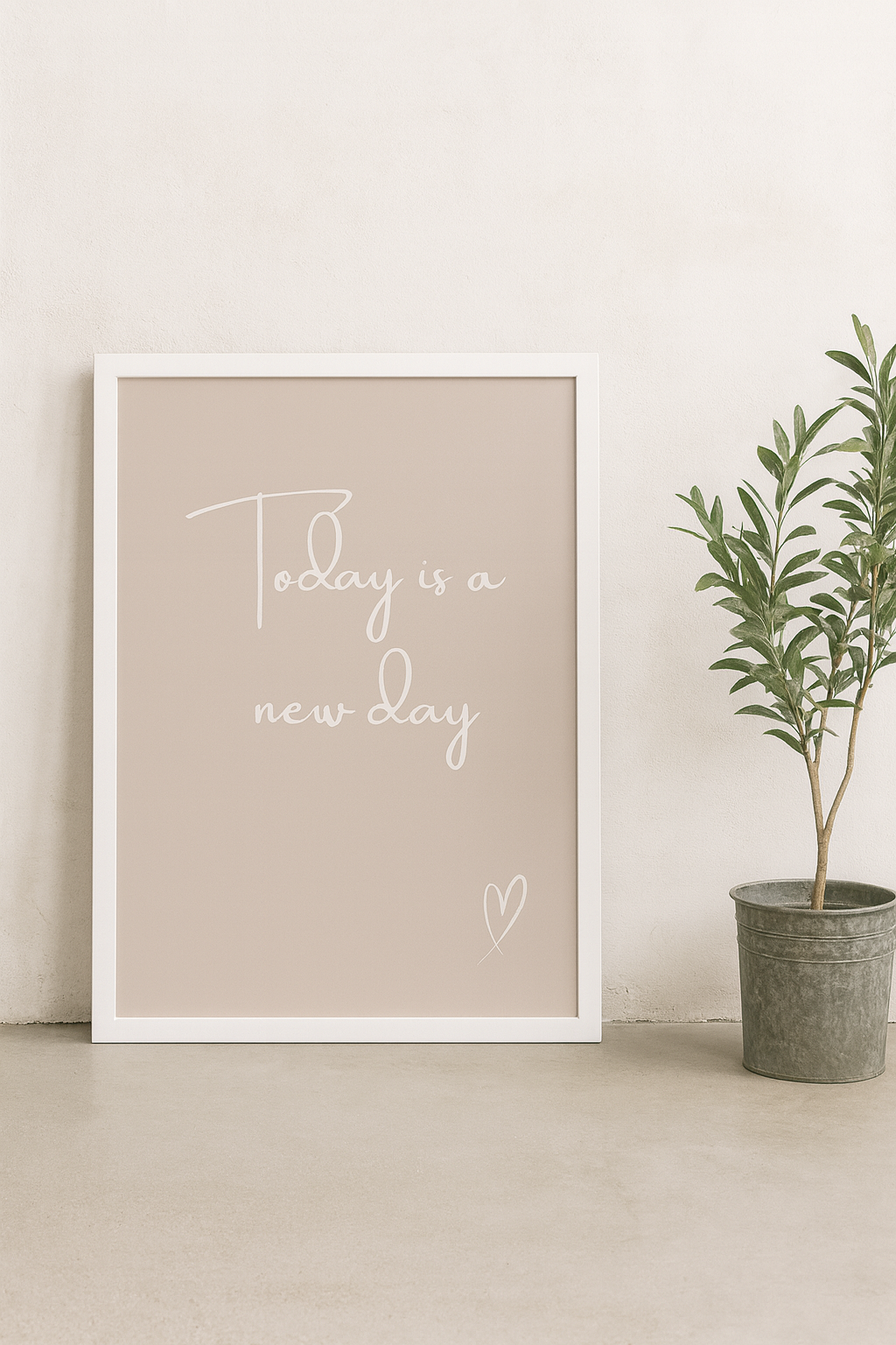 Framed print with 'Today is a new day' text on a white wall with a plant beside it.
