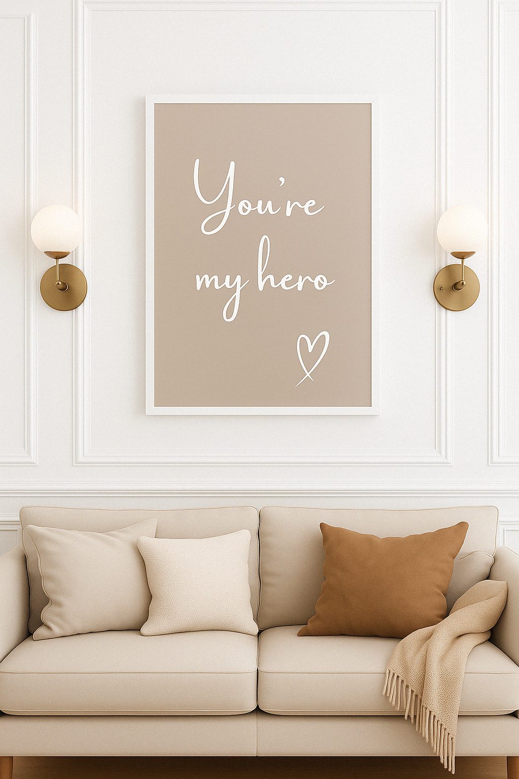 Beige wall with framed artwork displaying 'You're my hero' text, beige sofa with pillows and blanket.