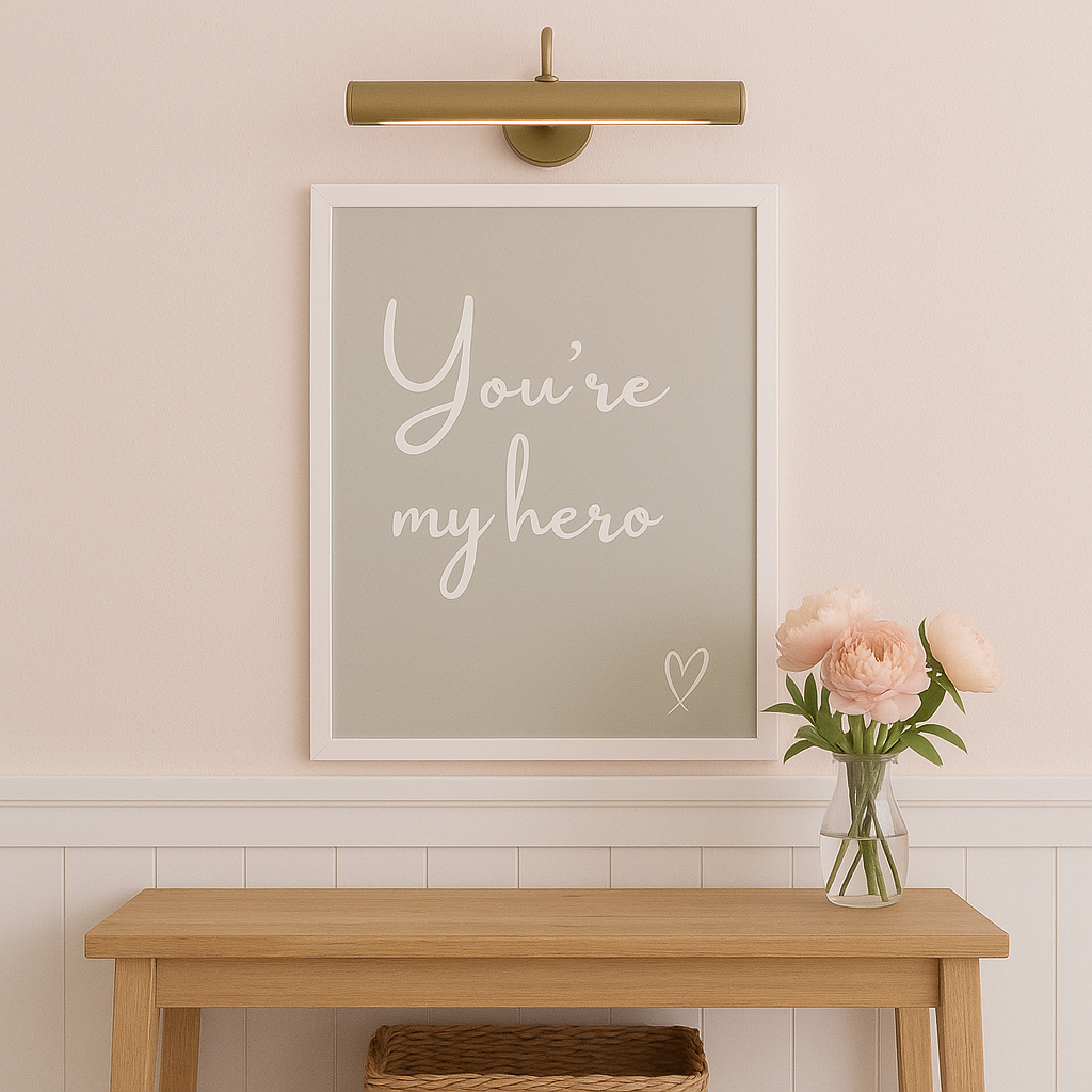 Framed artwork with 'You're my hero' text on a wall above a wooden bench with a vase of flowers.