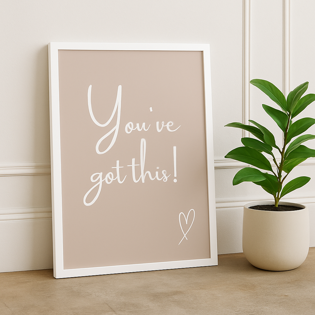 Framed motivational poster with 'You've got this!' text on a pink background, next to a potted plant.